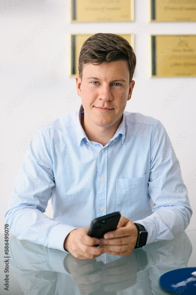 Positive male office manager in blue shirt sitting at glass tabl Positive male office manager in blue shirt sitting at glass tabl