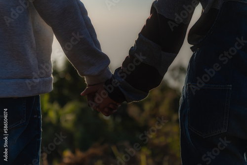 Closeup silhouette of a couple holding hands while walking watching the sunrise