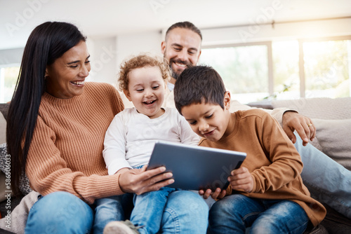 Family, tablet and children learning online in the living room of home with happy parents for child development. Education, funny video or internet with a father, mother and kids bonding on the sofa
