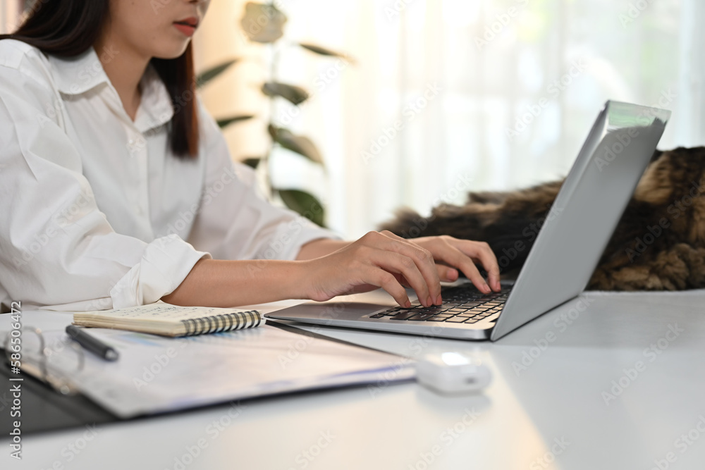 Cropped shot of young woman typing business email, working online on laptop at home office Cropped shot of young woman typing business email, working online on laptop at home office