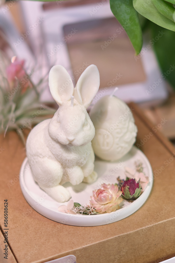 artisanal white rabbit candle and an Easter egg candle showcased on market stall during a festive event. Local markets or fairs promoting artisanal products. art of candle making and creative designs artisanal white rabbit candle and an Easter egg candle showcased on market stall during a festive event. Local markets or fairs promoting artisanal products. art of candle making and creative designs