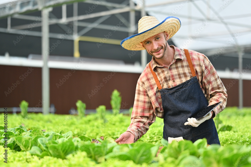 Obraz premium Farmer with digital tablet checking sustainable farming growth or progress in greenhouse. Business agriculture and technology concept