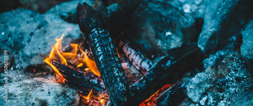 Vivid smoldered firewoods burned in fire close-up. Atmospheric warm background with orange flame of campfire. Unimaginable full frame image of bonfire. Burning logs in beautiful fire. Wonderful flame.