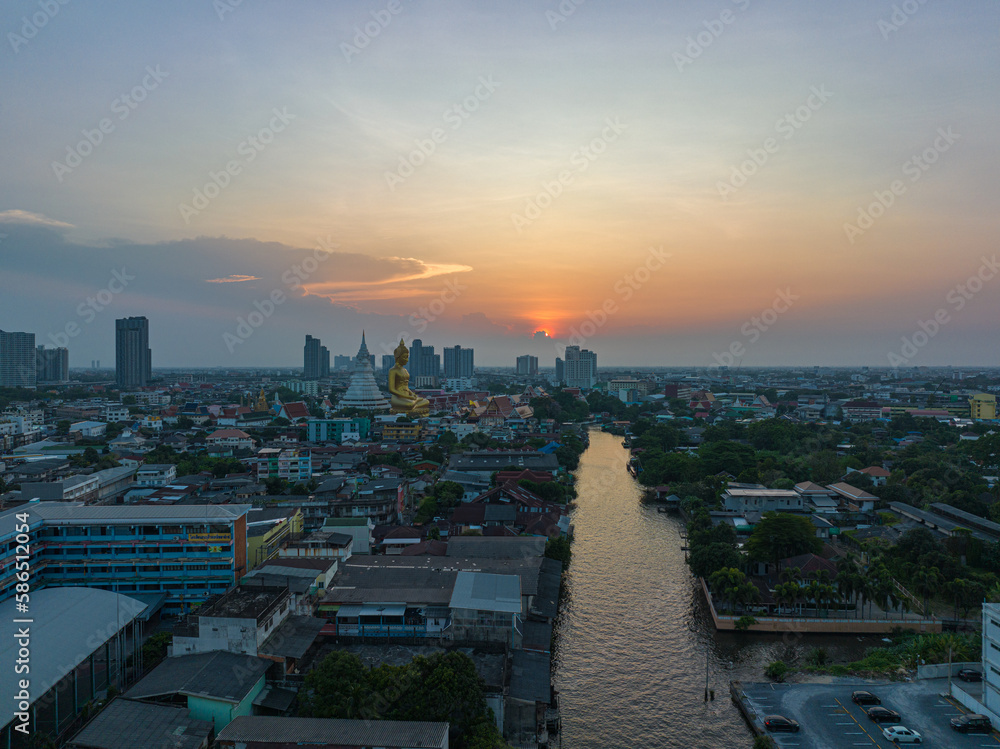 .aerial view golden big Buddha Wat Paknam Phasi Charoen in sunset. .beautiful sunset reflection on a canal in front big buddha. .scenery sky in twilight background.the one famous landmarks .aerial view golden big Buddha Wat Paknam Phasi Charoen in sunset. .beautiful sunset reflection on a canal in front big buddha. .scenery sky in twilight background.the one famous landmarks