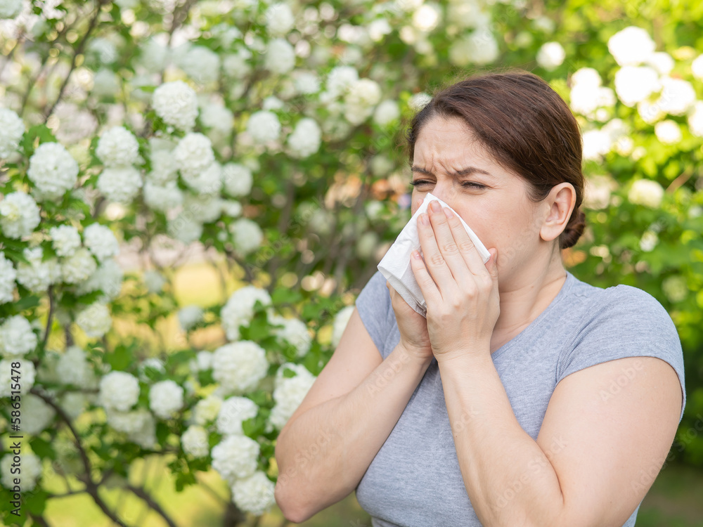 Caucasian woman suffers from allergies and sneezes while walking in the park. Caucasian woman suffers from allergies and sneezes while walking in the park.