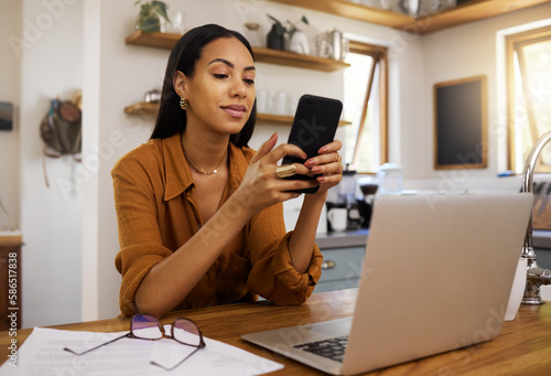 Remote work, phone and texting by business woman in kitchen with laptop, documents and form. Freelance, smartphone and female checking app, website or social media while working on online proposal