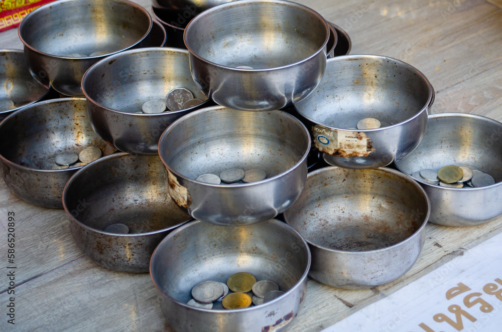 Metal bowls with coins for donations in a Buddhist temple Metal bowls with coins for donations in a Buddhist temple