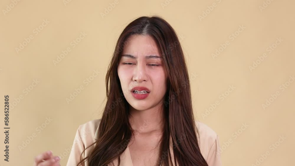 Young business Asian woman unhappy looking at camera isolated against a beige background. Girl looking angry and displeased Young business Asian woman unhappy looking at camera isolated against a beige background. Girl looking angry and displeased