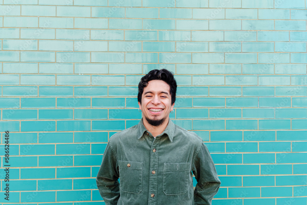 Smiling young man standing in front of brick wall Smiling young man standing in front of brick wall