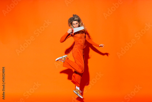 Wallpaper Mural Woman with hand saw jumping against orange background Torontodigital.ca