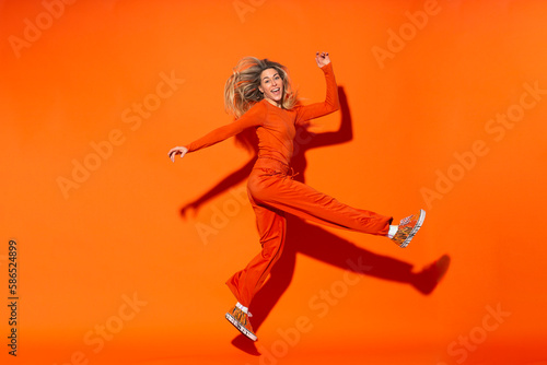 Woman making fake kick pose against orange background
