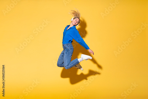 Carefree woman jumping in joy against yellow background photo