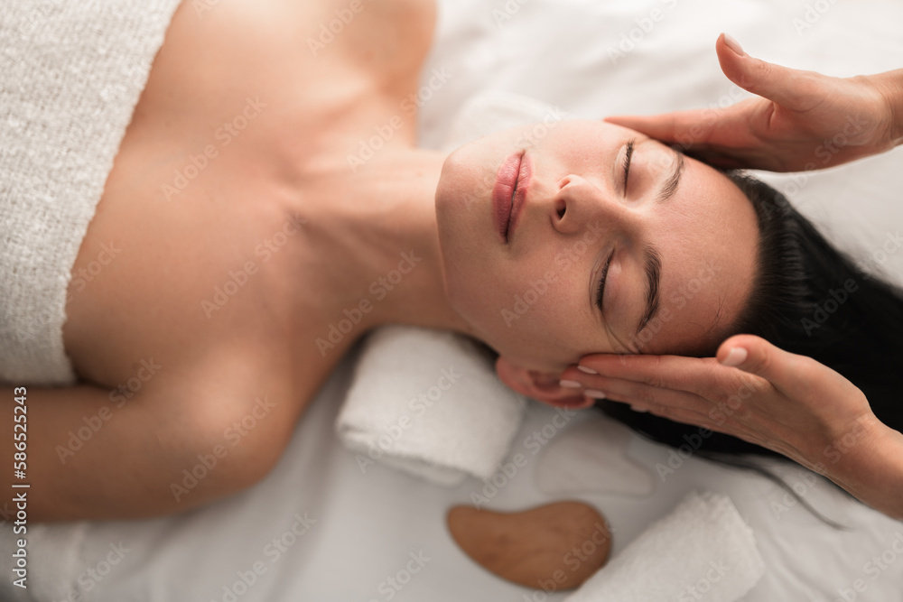 Masseuse massaging clients temples in spa salon Masseuse massaging clients temples in spa salon