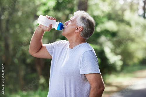 Man, exercise and outdoor drinking water for a run, workout and training for fitness. Senior male person with bottle for hydration, cardio health and wellness while running in nature and retirement