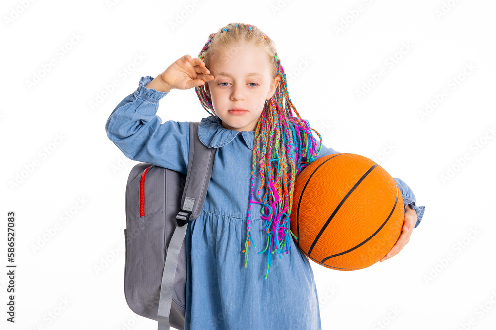 Beautiful small kid pupil shows sad exhausted tired emotions doesn't want to go to school first experience stands on white background with colorful braids wears rucksack backpack holds basketball ball Beautiful small kid pupil shows sad exhausted tired emotions doesn't want to go to school first experience stands on white background with colorful braids wears rucksack backpack holds basketball ball