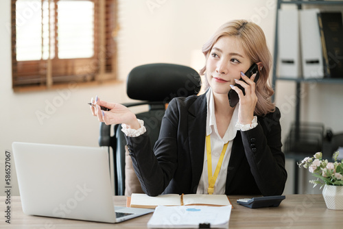 Close up on laptop in office, Asian happy beautiful businesswoman in formal suit work in workplace. Attractive female employee office worker smile.