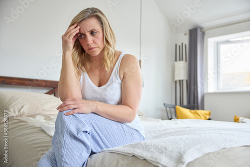 Принти на полотні Menopausal Mature Woman Suffering With Low Mood And Anxiety Sitting On Bed At Ho