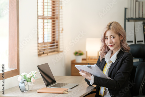 Close up on laptop in office  Asian happy beautiful businesswoman in formal suit work in workplace. Attractive female employee office worker smile.