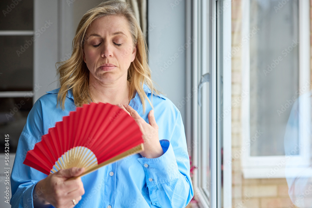 Menopausal Mature Woman Having Hot Flush At Home Cooling Herself With