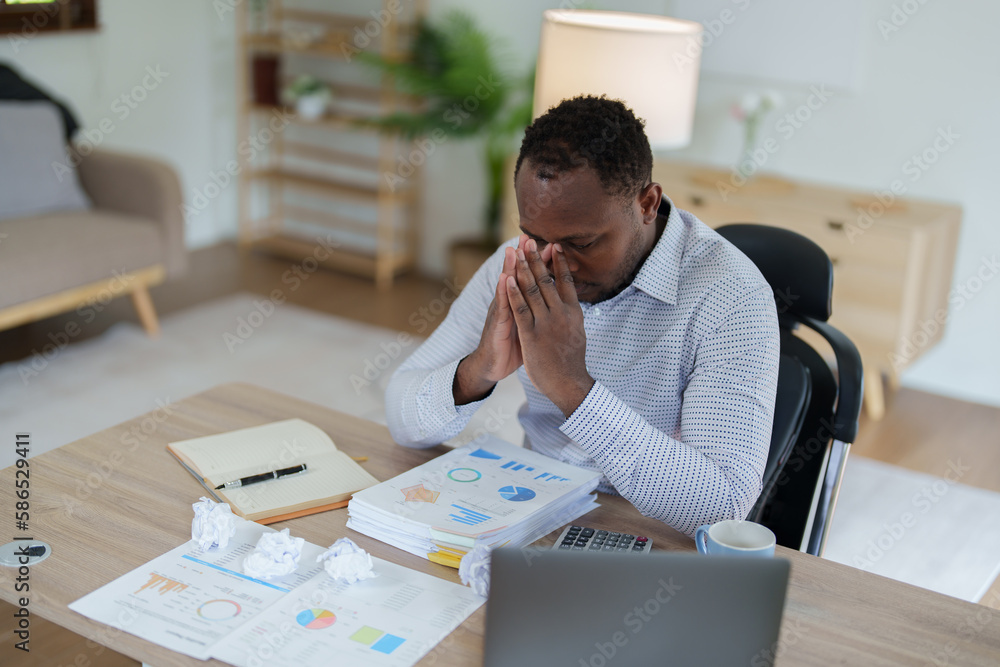 Burnout American African business man in stress works with many paperwork document, migraine attack, Freelance, work from home Burnout American African business man in stress works with many paperwork document, migraine attack, Freelance, work from home