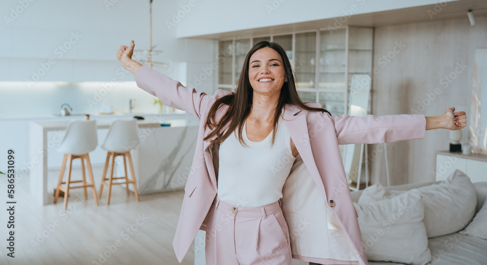 Grateful young businesswoman in light pink suit spreading hands toothy smiles wants to hug looks at camera. Brunette Korean successful student girl enjoying apartment. Tanned female relaxing home. Grateful young businesswoman in light pink suit spreading hands toothy smiles wants to hug looks at camera. Brunette Korean successful student girl enjoying apartment. Tanned female relaxing home.