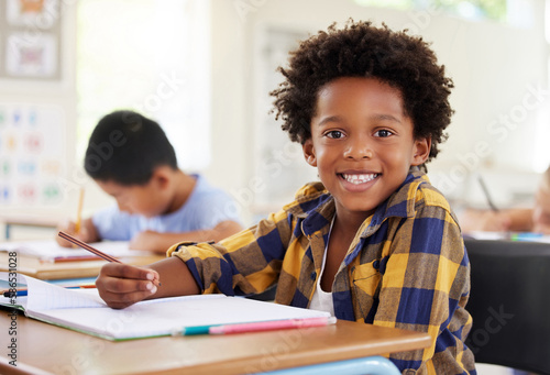 Education, drawing portrait or boy child in classroom learning, exam or studying with preschool notebooks. Development or kids or happy student with creative art writing for knowledge in kindergarten