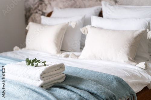 fresh terry towels prepared on bed with cushions and bedding