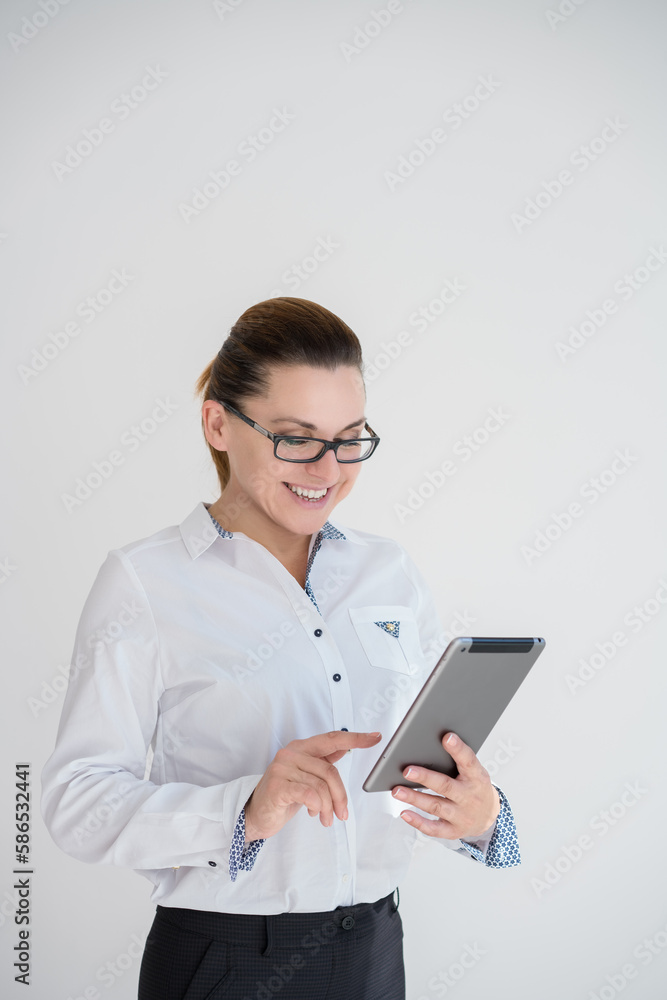 Image of young caucasioan woman in black costume wearing eyeglasses, company worker in glasses, smiling and holding digital tablet, standing over white background. Concept of success and technology. Image of young caucasioan woman in black costume wearing eyeglasses, company worker in glasses, smiling and holding digital tablet, standing over white background. Concept of success and technology.