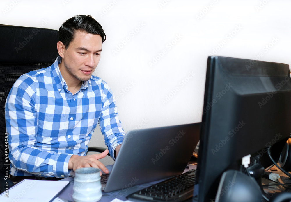 A man in a checked shirt working from home at a desk A man in a checked shirt working from home at a desk