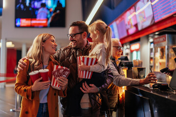 Happy family shopping in cinema hall.