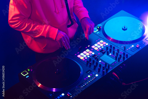 Hands of a DJ creating and regulating music on dj console mixer at club concert