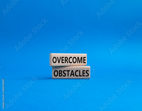 Overcome obstacles symbol. Concept words Overcome obstacles on wooden blocks. Beautiful blue background. Business and Overcome obstacles concept. Copy space.