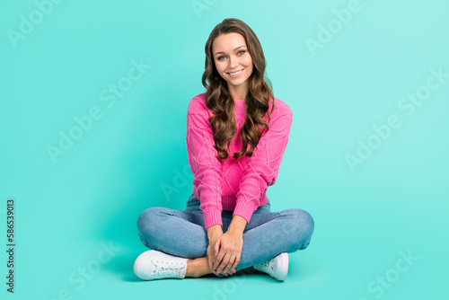 Full length photo of pretty cheerful lady dressed knitted pullover sitting legs crossed isolated teal color background