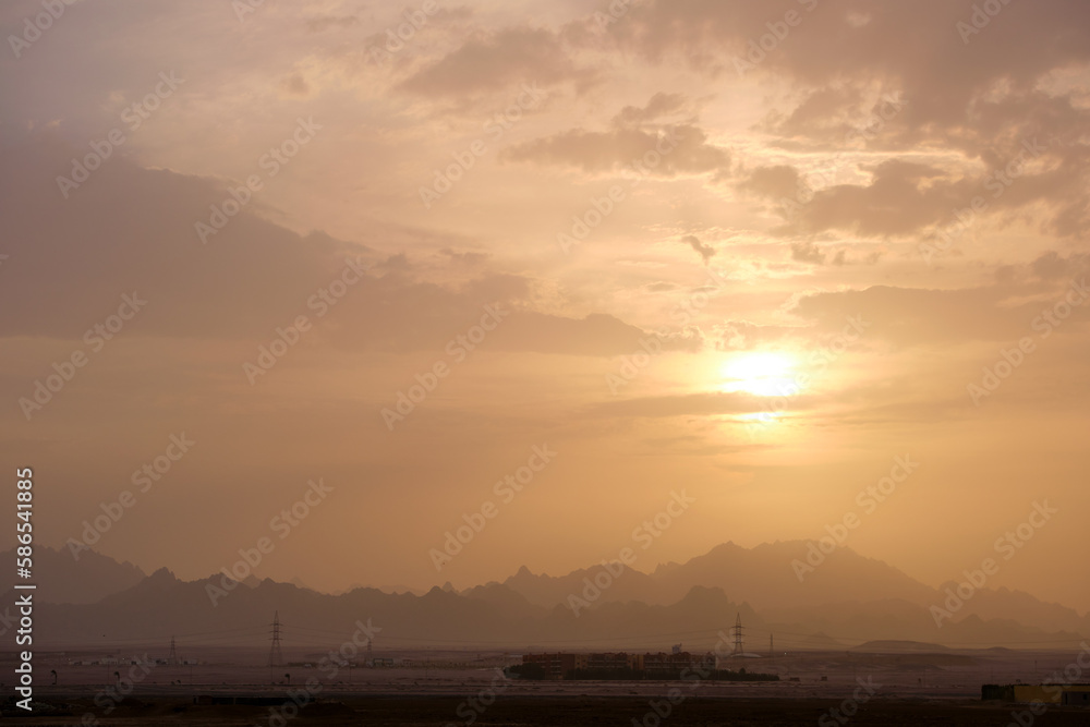 Sunset landscape with remote hotel complex against dark mountain peaks in egyptian desert