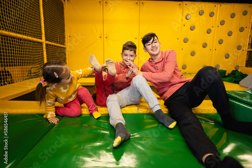 Kids together sit at playground park and give high five each other. Sisters and brothers in active entertaiments. photo