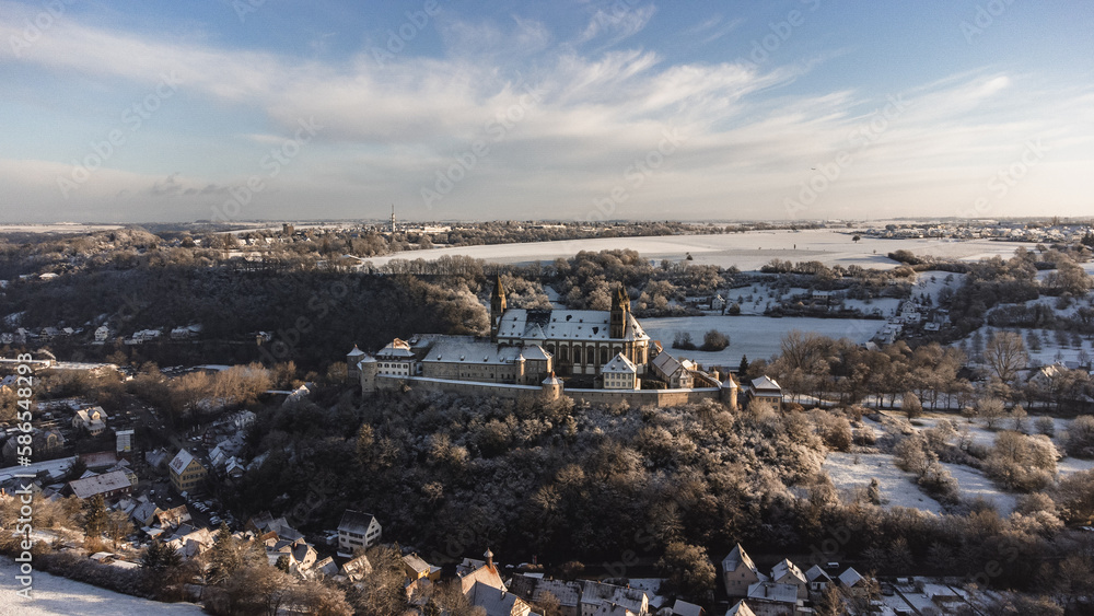 A castle that looks like Hogwarts in a winter landscape. The monastery looks like a castle, or a castle from the Middle Ages. The castle was photographed from the air with a drone