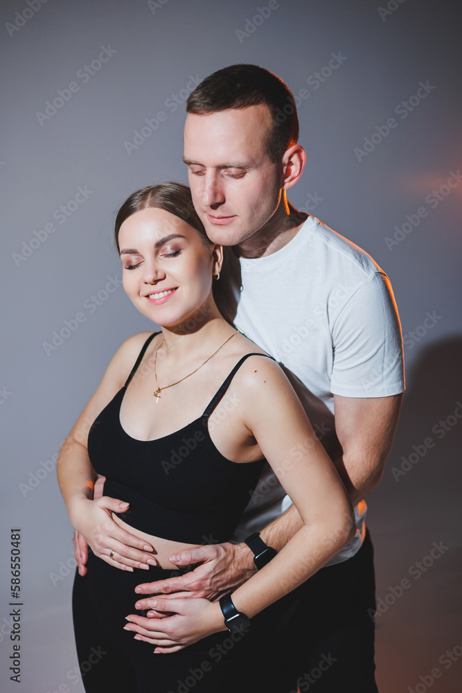 Cheerful happy young couple hugging on a plain background. A stylish man and a woman in love are tenderly embracing. Cheerful happy young couple hugging on a plain background. A stylish man and a woman in love are tenderly embracing.