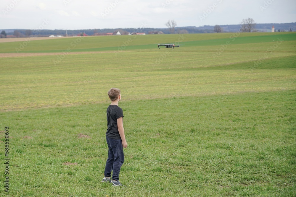 The boy controls the flight of the quadcopter using the remote control. The boy controls the flight of the quadcopter using the remote control.