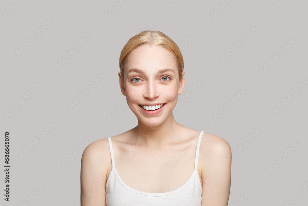 Portrait of glamorous woman in white top with straps with blonde hair laughing isolated on grey. Beauty, cosmetics, skincare, glamour Portrait of glamorous woman in white top with straps with blonde hair laughing isolated on grey. Beauty, cosmetics, skincare, glamour
