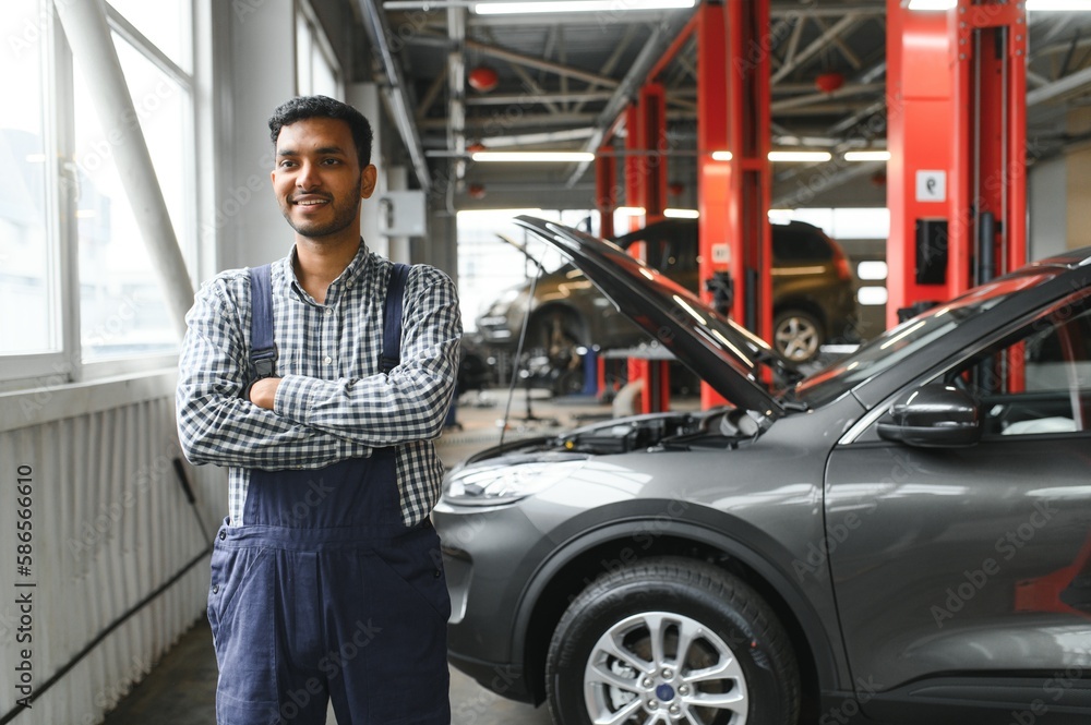 latin hispanic auto mechanic in uniform is examining a car while working in auto service latin hispanic auto mechanic in uniform is examining a car while working in auto service