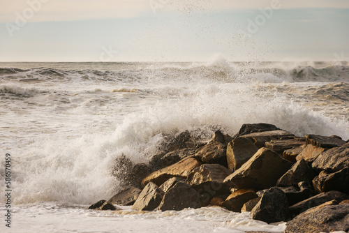 Golden sunset over the foam of waves breaking on the beach rocks. Espinho, Portugal