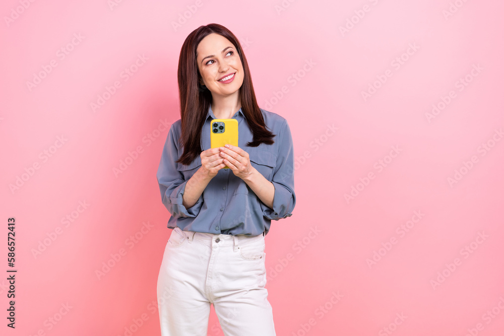 Photo of dreamy positive lady wear trendy blue clothes looking empty space novelty modern gadget isolated on pink color background Photo of dreamy positive lady wear trendy blue clothes looking empty space novelty modern gadget isolated on pink color background