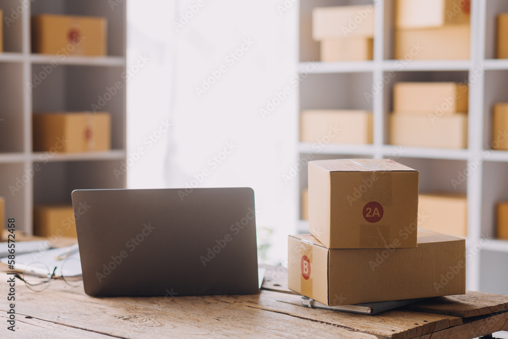 Startup SME small business entrepreneur of freelance Asian woman using a laptop with box Cheerful success Asian woman her hand lifts up online marketing packaging box and delivery SME idea concept Startup SME small business entrepreneur of freelance Asian woman using a laptop with box Cheerful success Asian woman her hand lifts up online marketing packaging box and delivery SME idea concept
