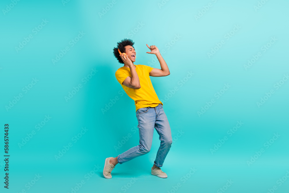 Full body photo of positive ecstatic person point fingers listen music headphones isolated on cyan color background Full body photo of positive ecstatic person point fingers listen music headphones isolated on cyan color background