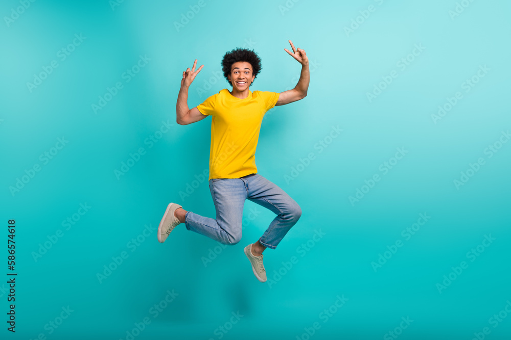 Full size photo of crazy active person jumping hands fingers show v-sign isolated on emerald color background