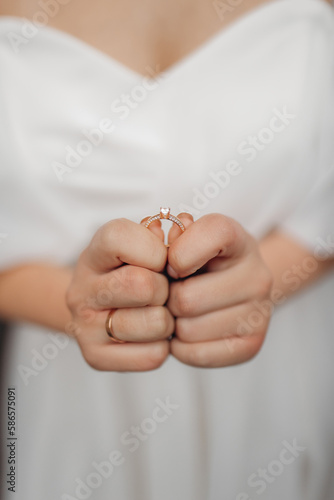 Close-up photo of the bride hands holding the wedding ring with both hands. Wedding ring before the proposal. Luxury wedding rings