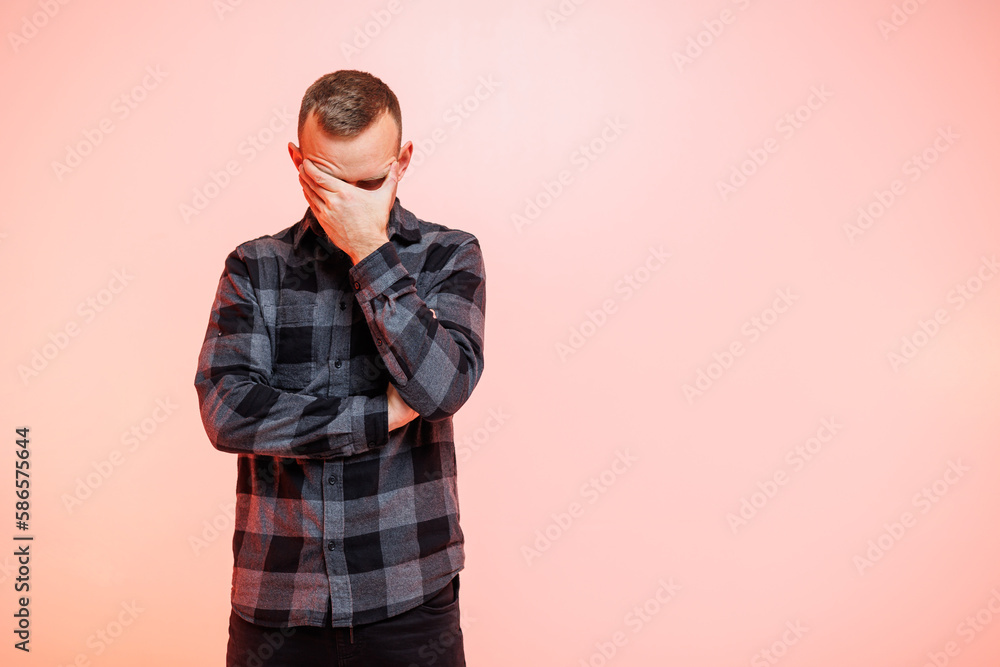 Young positive smiling man in a checkered shirt on a pink background. Place for text Young positive smiling man in a checkered shirt on a pink background. Place for text