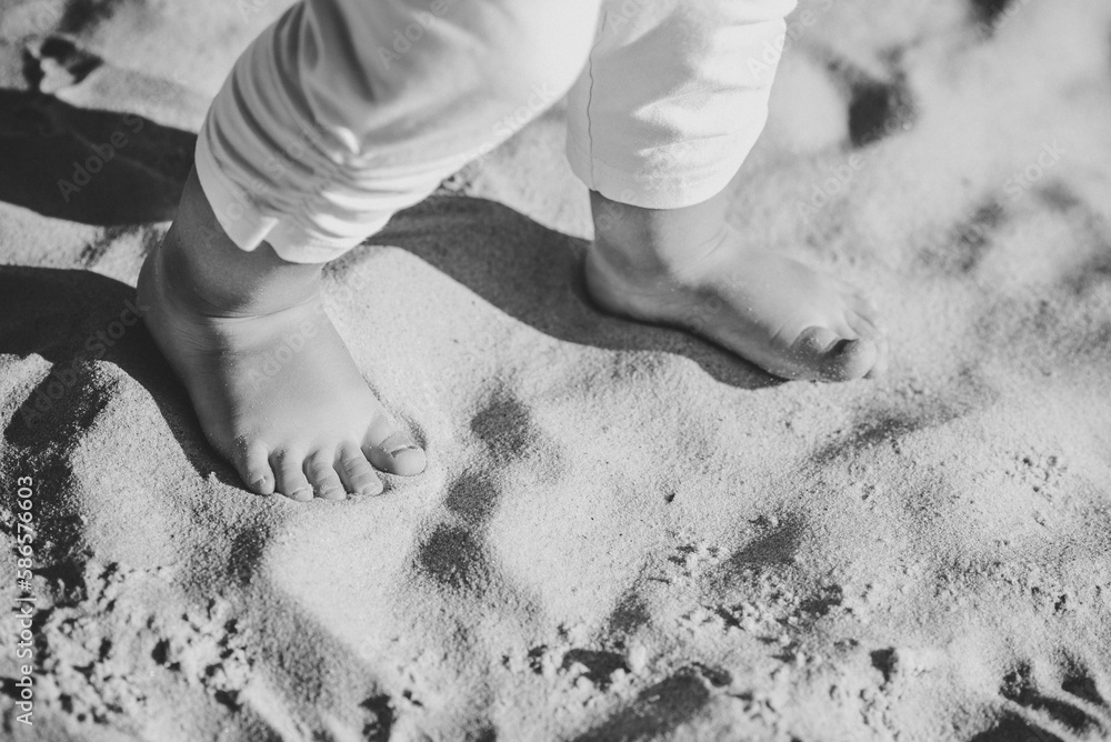 Baby feet barefoot walking on the sand on the sandy beach. Girl legs