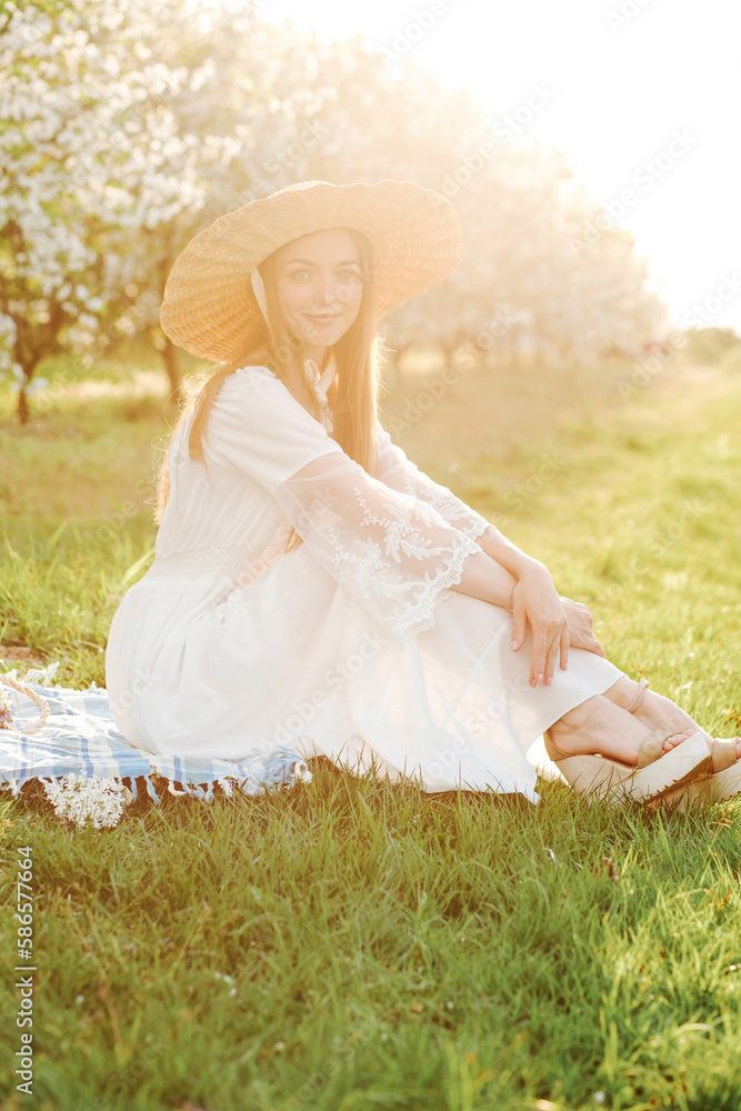 Amazing young woman in a straw hat posing in a garden of flowering trees in spring. Amazing young woman in a straw hat posing in a garden of flowering trees in spring.