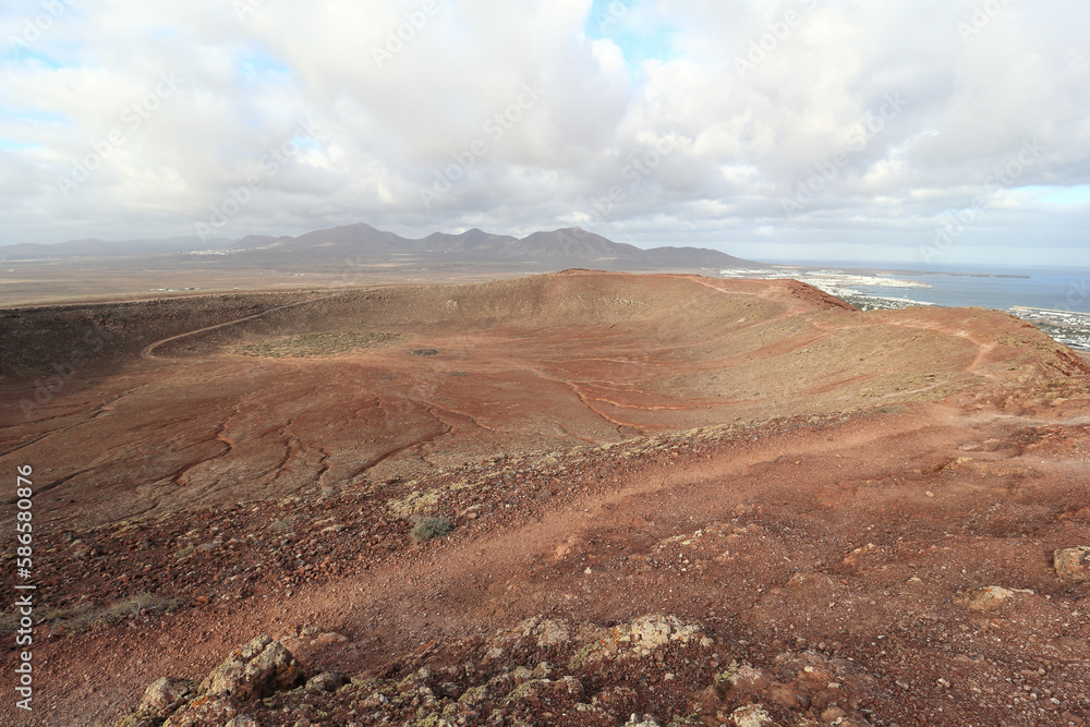 Captivating view of (Montaña Roja) Red Mountain's cone, Playa Blanca and surrounding landscape under dramatic cloudy sky in Lanzarote, Canary Islands